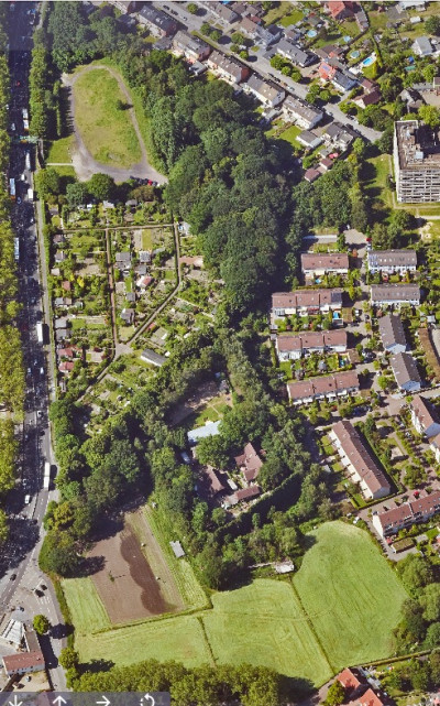 Luftaufnahme eines sehr grünen Stadtgebiets, Häuser, Felder und Straßen sind zu sehen