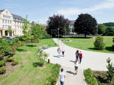 Wiesenumsäumter Platz vor einem großen Traditionsgebäude