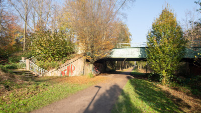 Grüner Fußweg der unter einer Brücke hindurch führt