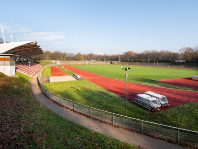 Eine Sportbahn mit Grünfläche, die Tribüne links im Bild